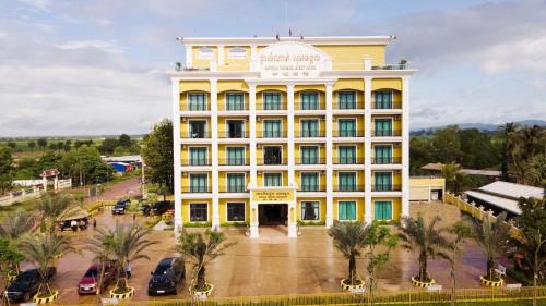 Phumĭ KhlângにあるSopheak Mongkol Guesthouseのヤシの木が目の前に広がる黄色い建物