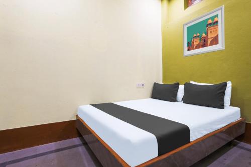 a bed in a room with a white and green wall at SPOT ON SR CONTINENTAL in Hyderabad