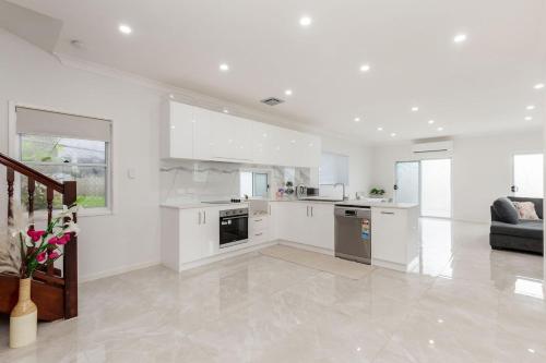 a kitchen with white cabinets and a living room at Entire House walk to South Bank mater in Brisbane