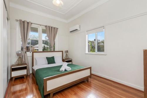 Un dormitorio con una cama y dos ventanas. en Entire House walk to South Bank mater, en Brisbane