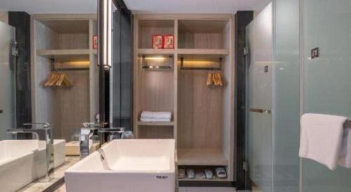 a bathroom with a sink and a tub and a mirror at Echarm Hotel Zibo Gaoqing Zhongcheng Inernational in Zibo