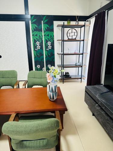 a living room with a wooden table and green chairs at 阿久津ハイツ201 in Tokyo