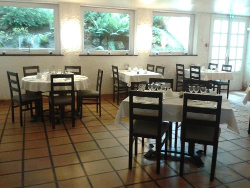 une salle à manger avec des tables et des chaises blanches et des fenêtres dans l'établissement Le Baudilois, à Pont-de-Larn