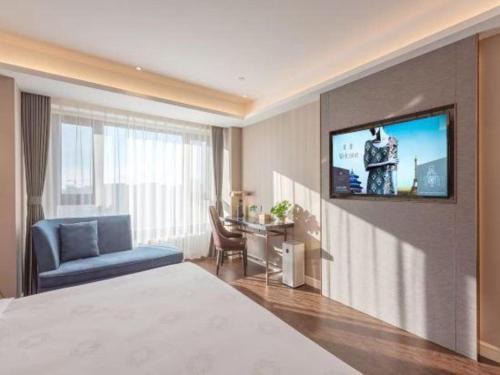 a hotel room with a bed and a tv on a wall at James Joyce Coffetel Harbin West High-speed Railway Station Wanda Plaza in Harbin