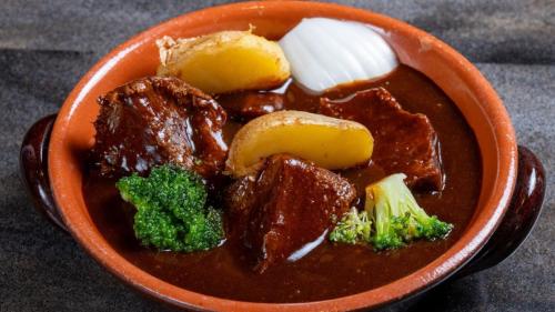 an orange bowl of food with meat and broccoli at APA Hotel Kobe Sannomiya Ekimae in Kobe