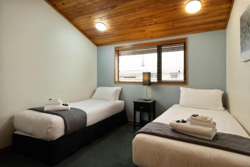 two beds in a small room with wooden ceilings at Riverside Hotel Marlborough in Blenheim