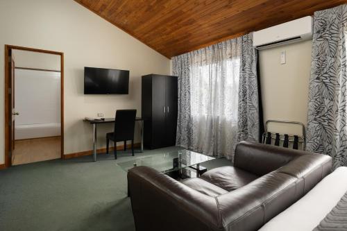 a living room with a leather couch and a table at Riverside Hotel Marlborough in Blenheim