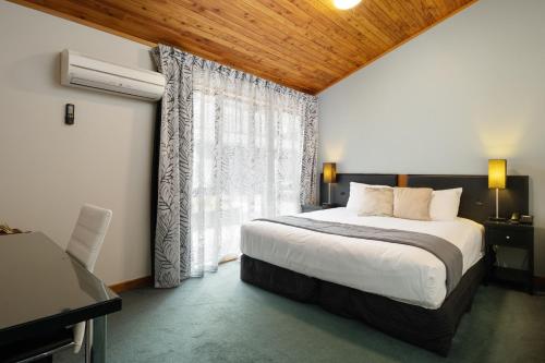 a bedroom with a bed and a large window at Riverside Hotel Marlborough in Blenheim