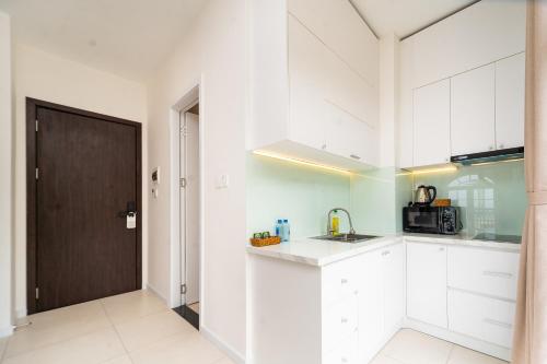 a kitchen with white cabinets and a brown door at Novus Sol Hotel & Apartment Sunset Town Phu Quoc in Phu Quoc