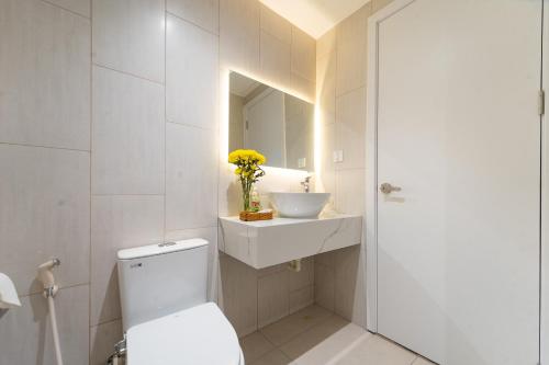 a bathroom with a toilet and a sink and a mirror at Novus Sol Hotel & Apartment Sunset Town Phu Quoc in Phu Quoc