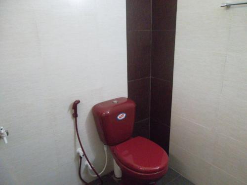 a bathroom with a red toilet in a stall at Lakeside Paradise in Kataragama