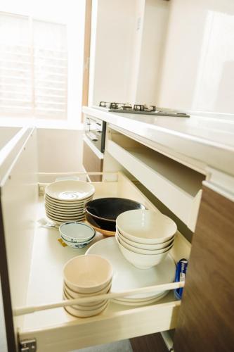 a kitchen with white plates and bowls on a shelf at X103Nagoya Station area courtyard rental detached house in Nagoya