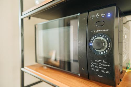 a black microwave oven sitting on a shelf at X103Nagoya Station area courtyard rental detached house in Nagoya
