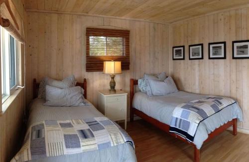 a bedroom with two beds and a lamp in it at Pourvoirie La Corneille in Havre-Saint-Pierre