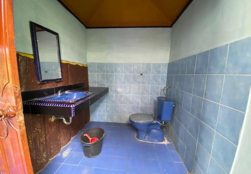 a bathroom with a blue toilet and a sink at Roman Sinasi Hotel By Secoms in Tongging