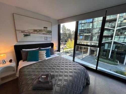 a bedroom with a large bed and a large window at 2BR-2BR-1Car-CBD-Pool-Shopping in Canberra