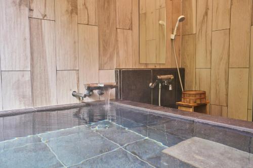 ニセコ町にあるUli Villa Onsenの水たまりと木製の壁があるバスルーム