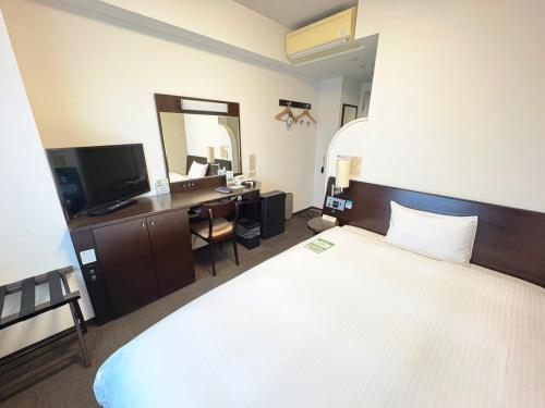 a hotel room with a large bed and a desk at Hotel Route-Inn Tsuruoka Ekimae in Tsuruoka