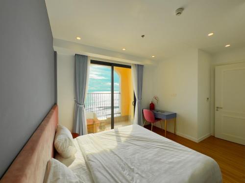 a bedroom with a bed and a desk and a window at Sunset town Phú Quốc in Phu Quoc
