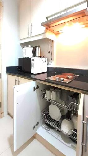 a kitchen with an open dishwasher with a microwave at CONDO Staycation Sea Residence MOA-Kharen in Manila