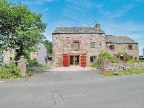 an old brick house with a red door on a street at Fenham Barn in Soulby