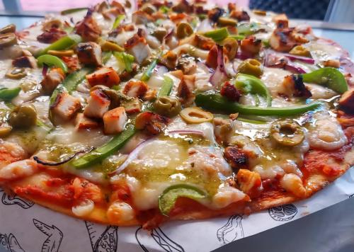 a pizza with green peppers and cheese on a table at Mayafair All Inclusive in Cancún