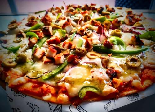 a pizza with cheese and vegetables on a plate at Mayafair All Inclusive in Cancún
