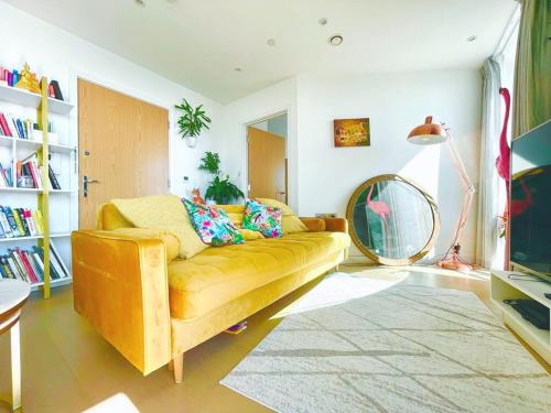 a living room with a yellow couch and a fan at Luxury 1-Bedroom Apt with Stunning London Views in Barking
