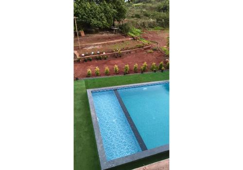 a garden with a swimming pool and a vegetable garden at Panchgani Palace in Panchgani