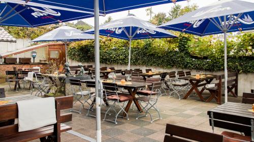 a patio with tables and chairs with blue umbrellas at Gasthaus Otto in Königswinter