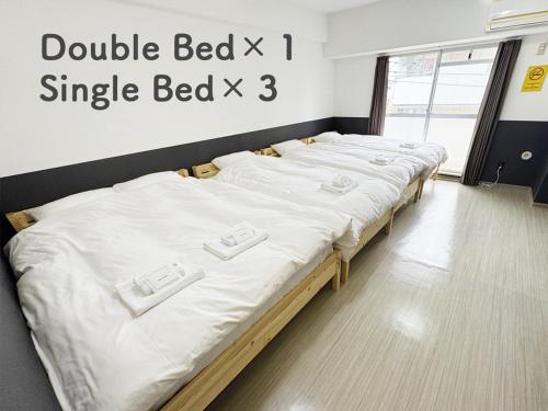a large bed with white sheets in a room at Hostel Inn Yokohama Isezakicho in Yokohama