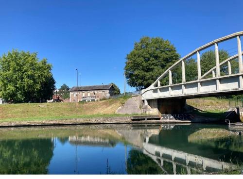 un pont sur une rivière avec une maison en arrière-plan dans l'établissement Logement Omissy, 