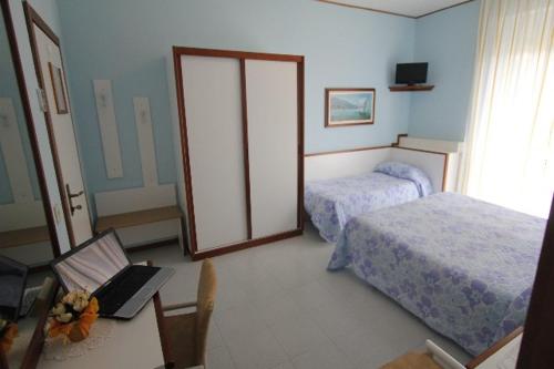 een slaapkamer met 2 bedden en een laptop op een tafel bij Hotel Liliana Andora citr 9006-0004 in Marina dʼAndora