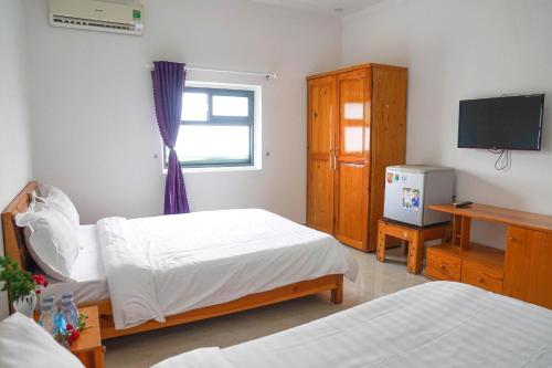 a bedroom with two beds and a tv and a window at Lotus Hotel & Café in Ðưc Trọng