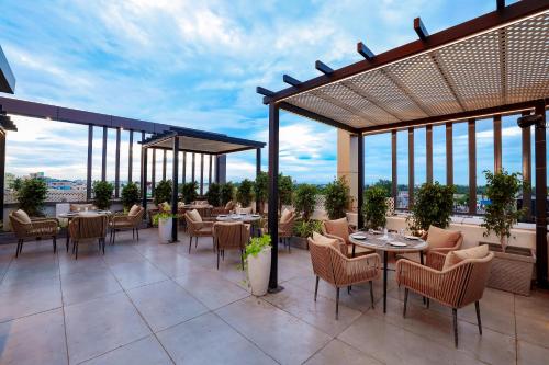 ein Restaurant mit Tischen und Stühlen auf einer Terrasse in der Unterkunft Sathyam Oasis in Tiruchchirāppalli