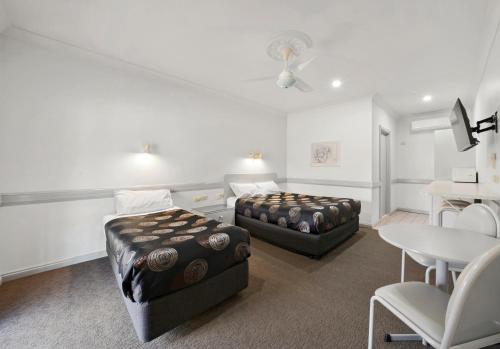 a room with two beds and a table and chairs at Centre Town Motel in Nagambie