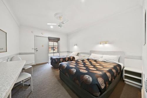 纳甘比Centre Town Motel的一间卧室，配有一张床、一张桌子和几把椅子