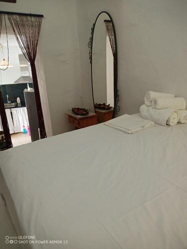 a bedroom with a white bed with a mirror at ''RENATA'' Studio in Kithnos