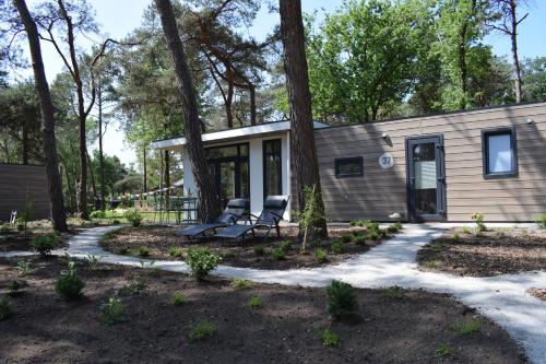 a small house with two chairs in front of it at Boshuisje - Bos en Bliss in Haarle