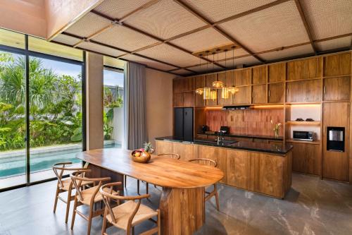 an open kitchen with a wooden table and chairs at TUI BLUE Berawa Hotel and Villas in Canggu
