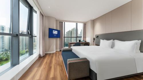 a hotel room with a large bed and large windows at Holiday Inn Express Chengdu Pidu by IHG in Chengdu