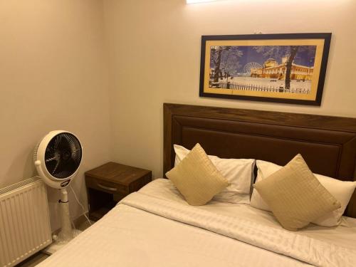a bedroom with a bed with white sheets and a fan at amlak Resorts Apartment Suite Bhurban in Bhurban