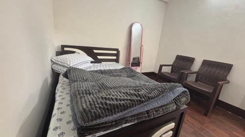 a bedroom with two beds and two chairs at Sherpa's Homestay in Kurseong