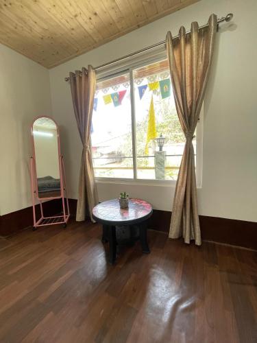 a room with a table in front of a window at Sherpa's Homestay in Kurseong