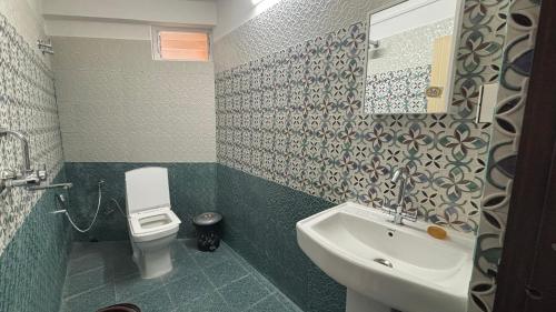 a bathroom with a white sink and a toilet at Sherpa's Homestay in Kurseong
