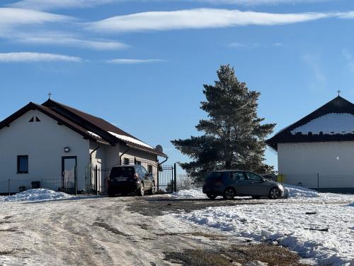two cars parked in front of a house in the snow at Colț de Rai in Ilva Mare
