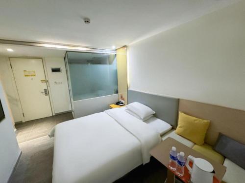 a bedroom with a large white bed and a table at 7 Days Inn Harbin West Railway Station in Harbin
