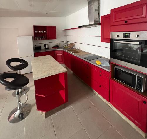 - une cuisine rouge avec des placards rouges et une cuisinière dans l'établissement Appartement PMR jacuzzi, à Argelès-sur-Mer