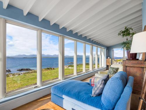 a living room with a blue couch and large windows at Suantrai Cottage in Roundstone