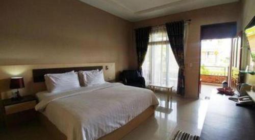 a bedroom with a large white bed and two windows at Samosir Cottages Resort in Tuk Tuk